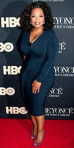 a woman in a blue dress standing on a red carpet with her hand on her hip