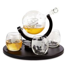 three glasses and a decanter are sitting on a tray with a globe in the background