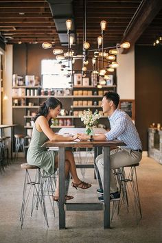 a man and woman sitting at a table in front of a book shelf filled with books