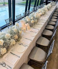 a long table is set up with white flowers and place settings for the dinner guests