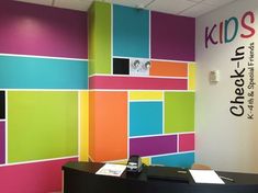 an office with brightly colored walls and a black desk in front of the wall has a phone on it