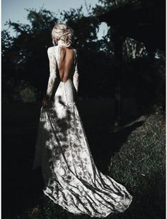 a woman in a white dress is standing on the grass with her back to the camera