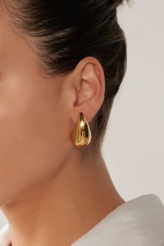 STYLE DETAILS: Indulge in the opulent Halcyon Earring. With its oversized teardrop shape in stainless steel or gold plating, this earring exudes sophistication and elegance. A timeless design that will transcend seasons, it will become a piece you'll reach for again and again, no matter the occasion. FEATURES: Drop design Stud closure Gold Plated, Stainless Steel 3cm length Modern Metal Teardrop Earrings For Pierced Ears, Modern Gold Teardrop Pendant, Modern Metal Drop Earrings For Pierced Ears, Modern Gold Teardrop Drop Earrings, Gold Single Drop Earring In Modern Style, Gold Modern Teardrop Earrings, Modern Gold Teardrop Earrings, Metal Drop Hoop Earrings, Classic Metal Teardrop Pierced Earrings