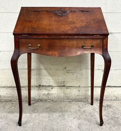 an old wooden desk with two drawers and one drawer on the top, against a white brick wall