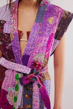 a woman wearing a purple dress with colorful designs on the front and back, tied to her waist