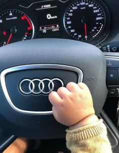 a small child's hand on the steering wheel of a car with dashboard gauges