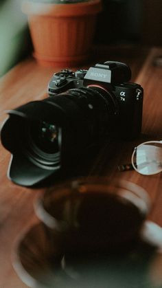 a camera sitting on top of a wooden table next to a bowl and spoons