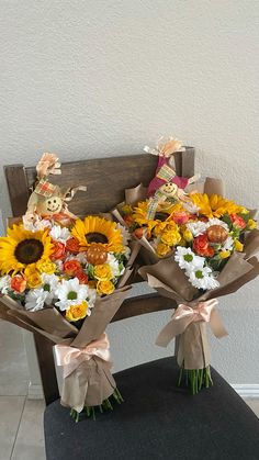 two bouquets of sunflowers and other flowers on a bench with ribbon tied around them