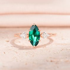 an emerald and diamond ring sitting on top of a table