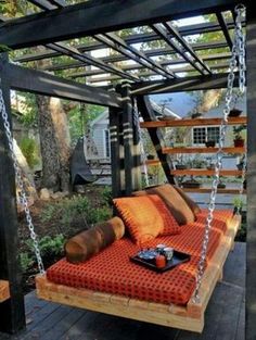 an outdoor swing bed made out of pallet wood with cushions and chains attached to it