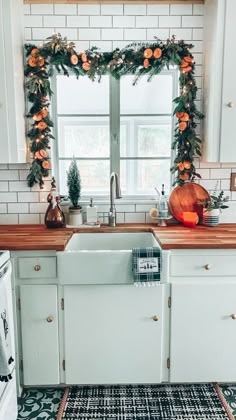 a kitchen decorated with greenery and orange flowers