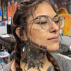 a woman with tattoos on her face and neck is looking at the camera while wearing glasses