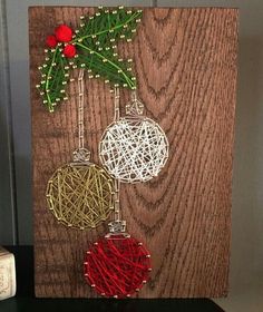 three christmas ornaments are hanging on a wooden board with string and bead work in the shape of baubles