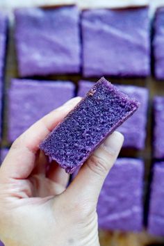 a hand is holding a purple sponge in front of some squares of blue colored food