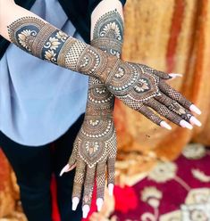 a woman's hands with hennap on her arm and hand, showing the intricate