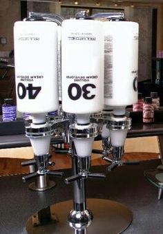 three white candles are sitting on top of a stand in front of a countertop