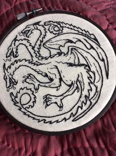 a white embroidered dragon with black outline on a red background is shown in the shape of a circle