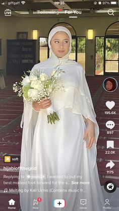 a woman in a white dress holding a bouquet and wearing a veil on her head