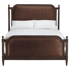 a brown bed with white pillows on top of it and a wooden frame around the headboard