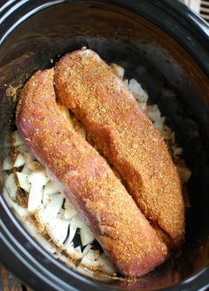 two fish fillets in a crock pot with onions and seasoning on the side