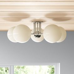 a ceiling light that is hanging from the ceiling in a room with white walls and windows