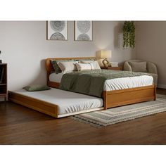 a bed sitting on top of a hard wood floor next to a dresser and lamp