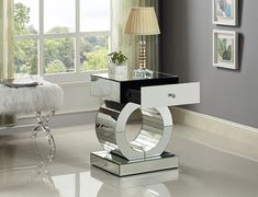 a mirrored end table with a lamp on top in front of a window and a chair