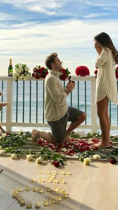 a man kneeling down next to a woman in front of flowers and candles on the ground