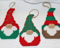 three needled christmas ornaments on a white towel, one is red and the other is green