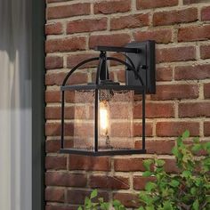 a light that is on the side of a brick wall next to a potted plant