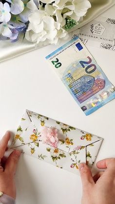 the person is making an origami envelope with flowers on it and paper money