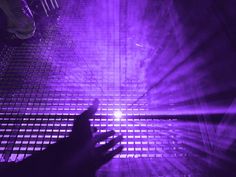 a person's hand reaching up towards a purple light