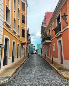 an empty cobblestone street lined with colorful buildings