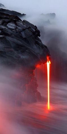 an orange light emitting from the lava in the ocean with rocks and water around it