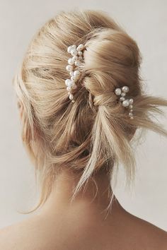 a woman with her hair in a bun and some pearls on the back of her head