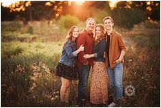 three people standing together in a field at sunset