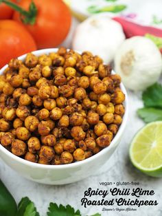 a white bowl filled with chickpeas next to some tomatoes and lime wedges