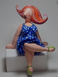 a ceramic figurine of a woman sitting on top of a white block with polka dots