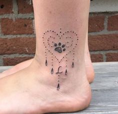 a dog's paw and heart tattoo on the side of a foot with rain drops