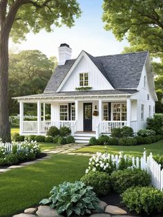 a small white house surrounded by lush green grass and flowers in front of the door