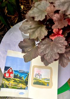 an open book sitting on top of a table next to a potted plant with leaves