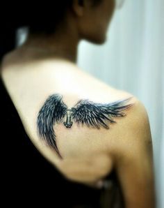 the back of a woman's shoulder with an angel wing tattoo on it