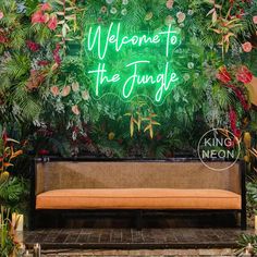 a bench sitting under a neon sign that reads welcome to the jungle