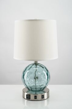 a glass table lamp with a white shade