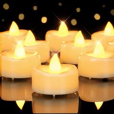 many lit candles are arranged on a reflective surface