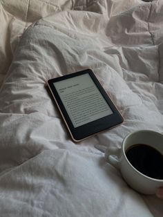 a cup of coffee and an electronic device on a bed