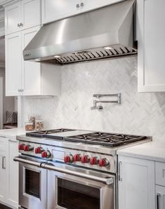 a stove top oven sitting inside of a kitchen next to white cupboards and drawers