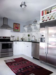 a kitchen with stainless steel appliances and white cupboards, including a rug on the floor