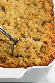 a close up of a casserole in a white dish with a spatula