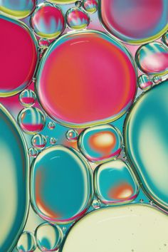 an image of oil and water drops in the color blue, pink, yellow and green